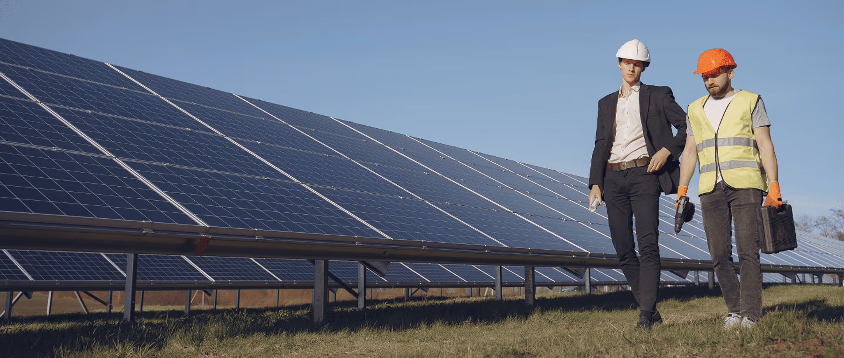 A couple of men standing next to each other in front of a solar panel.